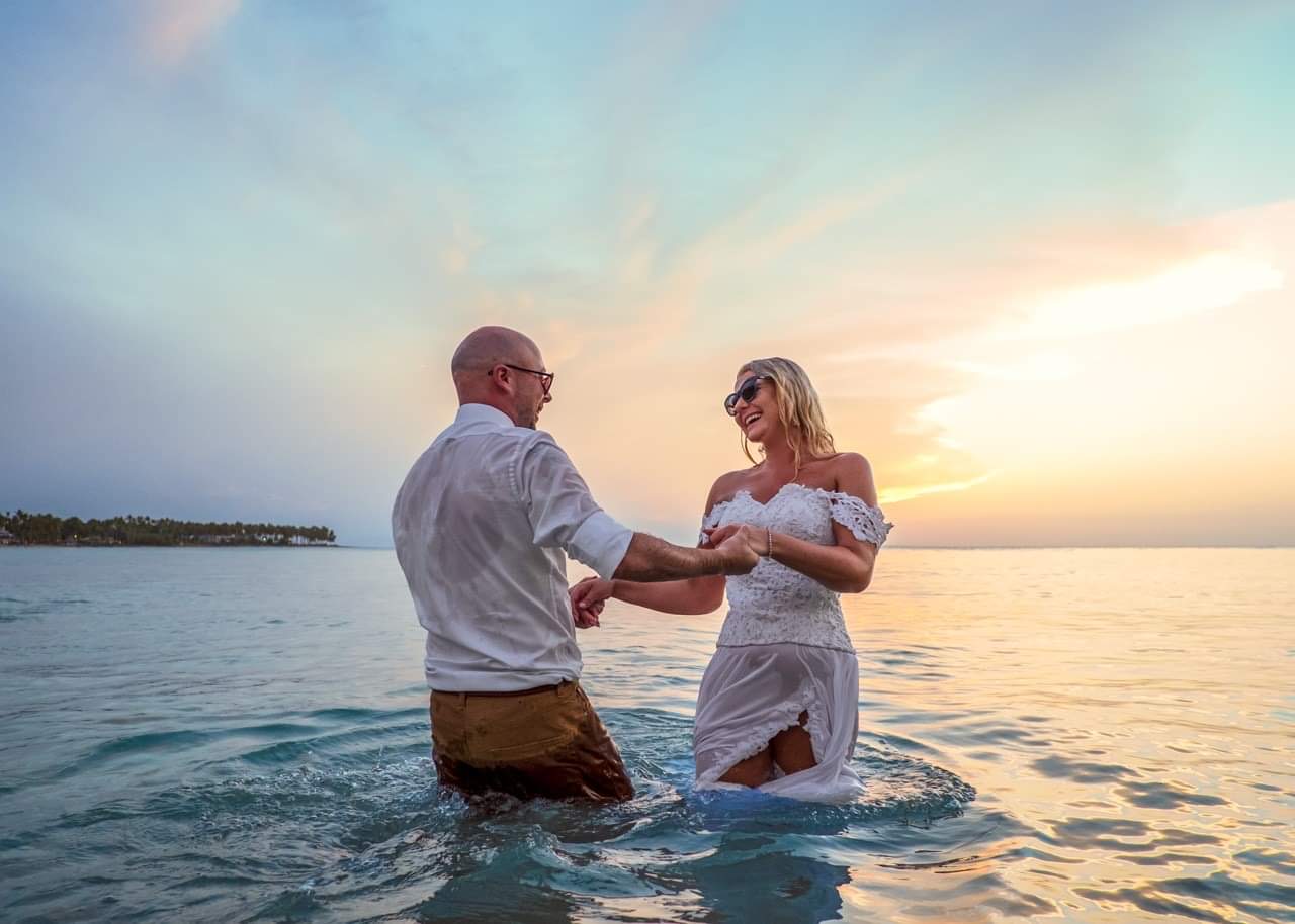 Bride and groom laughing in the sea at sunset – bridal laser hair removal in Leighton Buzzard